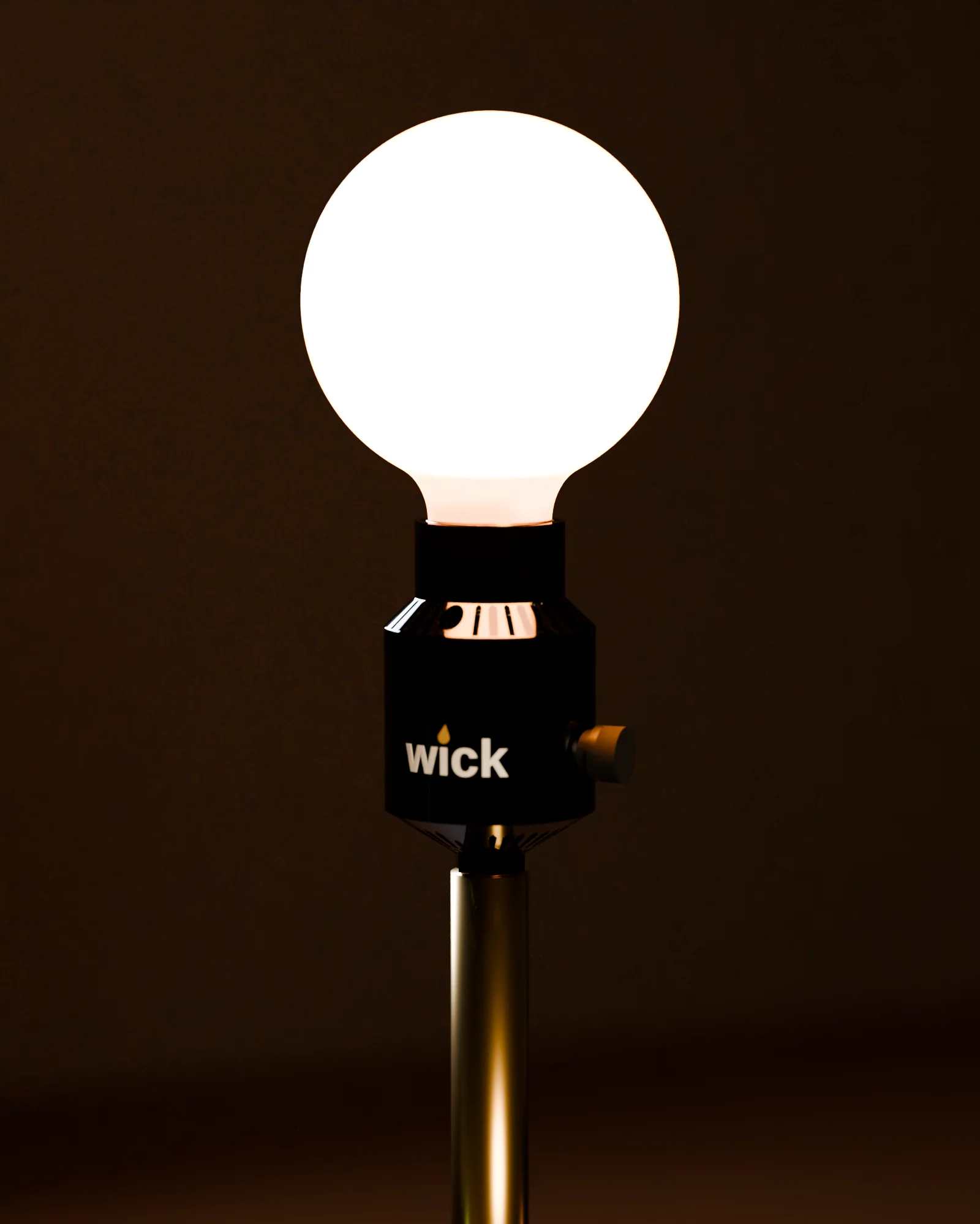A walnut and brass table lamp with a bare amber globe on a black wick socket